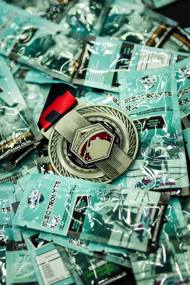Pile of WOD Powders sachets with a competition medal